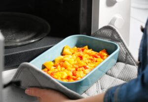 Taking out baking dish with dinner from microwave oven during moving week