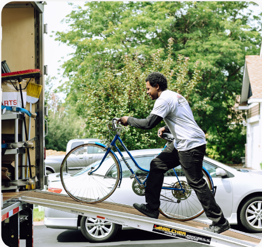 Man pushing a bicycle up a moving truck's ramp