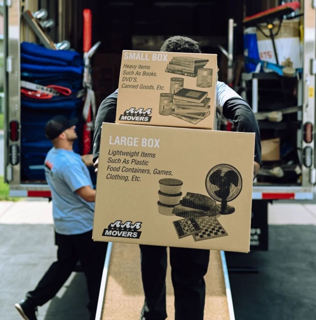 AAA Movers crew carrying a large shrink-wrapped item out through a front doorway, with a moving pad strapped to the door frame to protect it